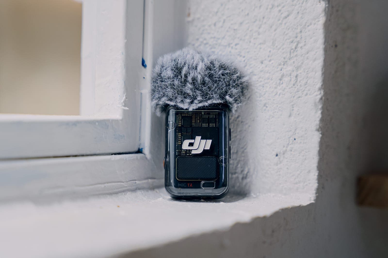 Bộ phát DJI Mic 2 gắn chụp lọc gió, đặt trên bệ cửa sổ trắng
