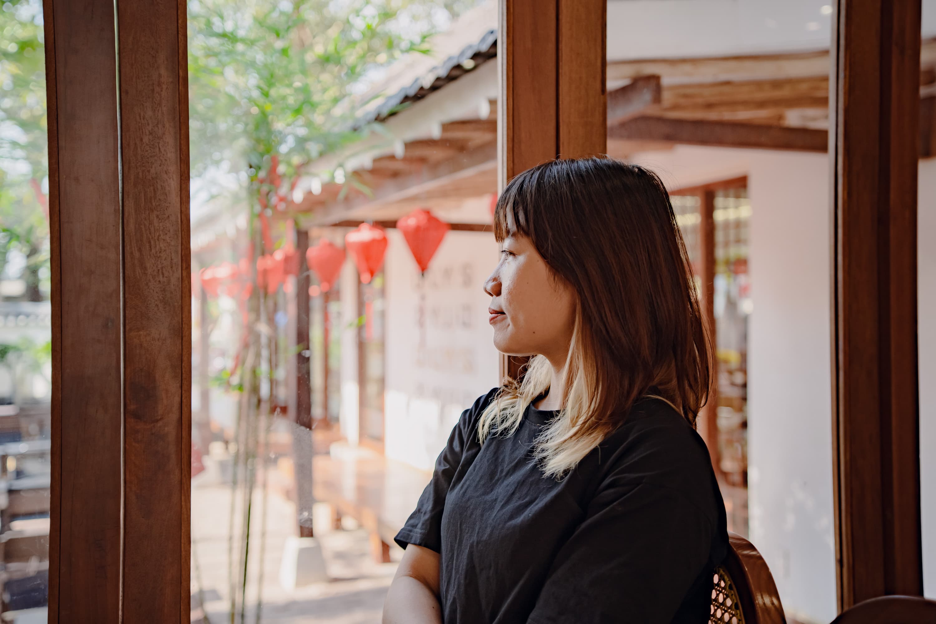 Xuân nhìn ra ngoài cửa sổ, phía sau là những chiếc đèn lồng đỏ